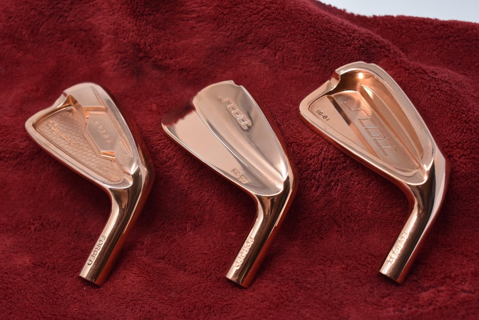 Three metallic golf club heads displayed.