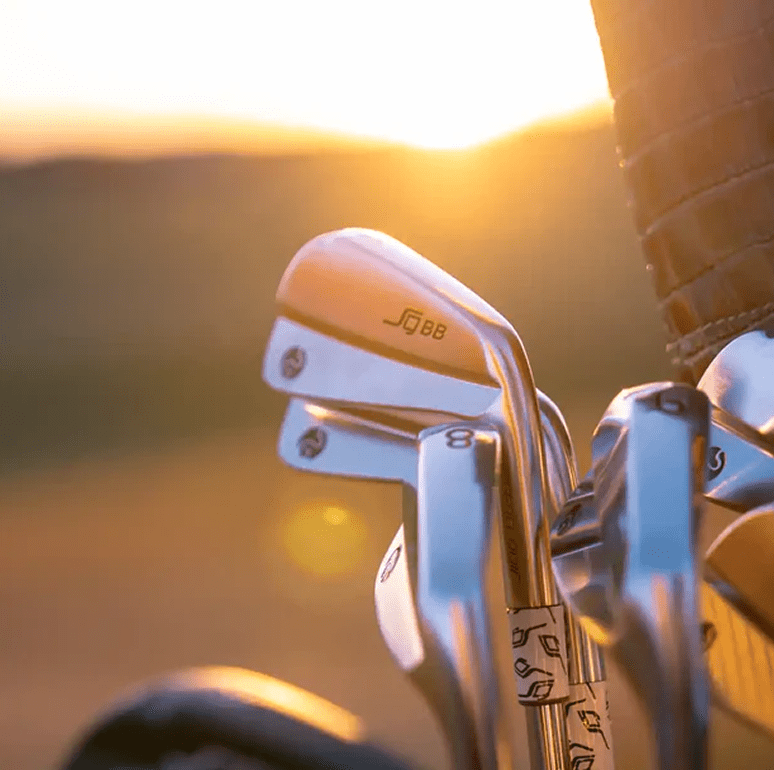 Shiny golf clubs with sunset glow