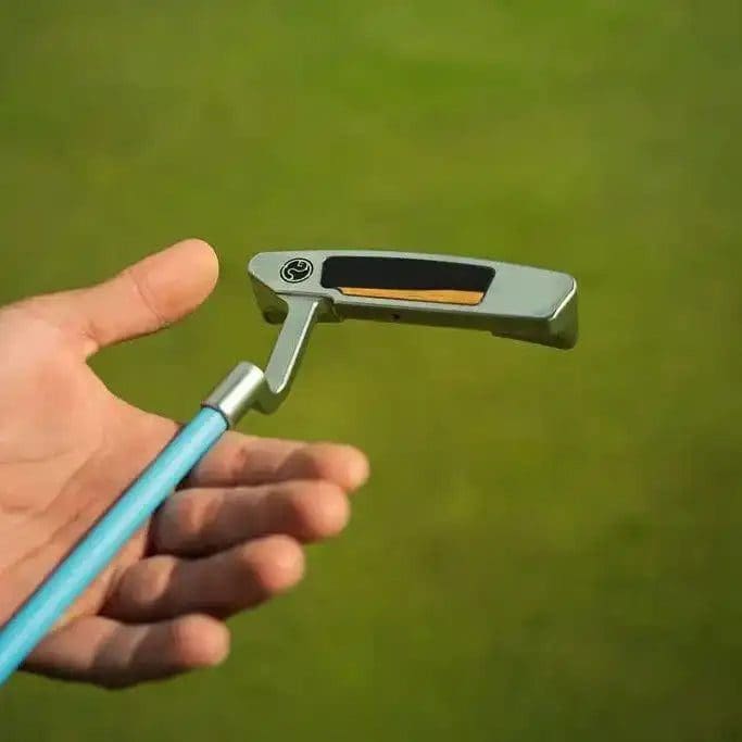 Golf putter held on green grass